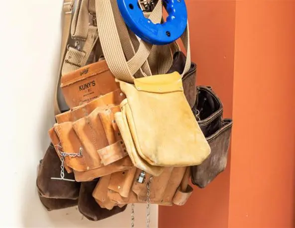 A woman wearing a PPE (hard hat and safety glasses) working with tools