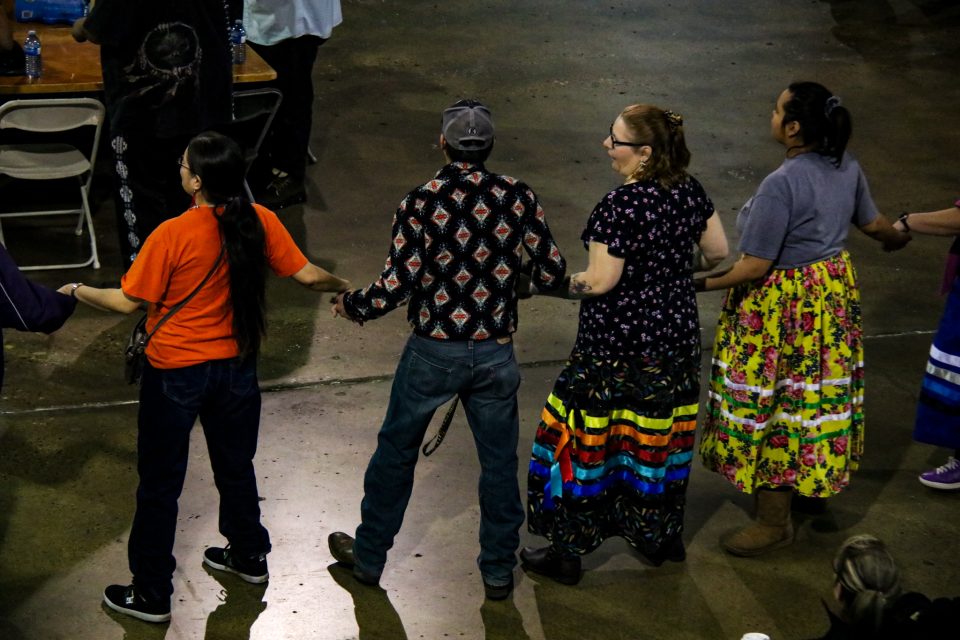 Four participants in the Round Dance move around the circle during the ceremony, linked together